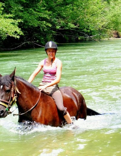Femme à cheval au milieu d'un cours d'eau